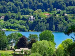 widok na jezioro z drzewami i domami w obiekcie Ferienwohnung am Wörthersee Villa Waldbach w mieście Krumpendorf am Wörthersee