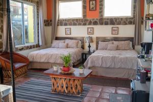 a bedroom with two beds and a table at El Rincón Del Valle en la Ruta Del Vino in Valle de Guadalupe