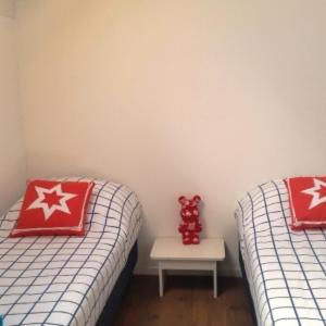 2 Betten mit roten und weißen Kissen und einem Tisch in der Unterkunft Roggebroek 27 in Stavoren