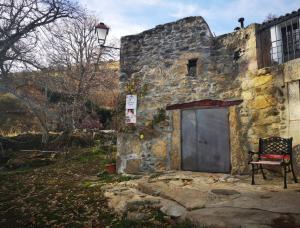 un vecchio edificio in pietra con una porta e una sedia di El Patio Chico a Los Loros