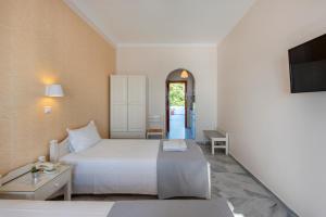 a bedroom with a white bed and a television at Irene Studios - Beachfront in Parikia