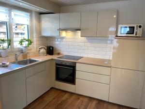 a kitchen with white cabinets and a sink and a refrigerator at S&P Mountain View Apartment 1 in Wilderswil
