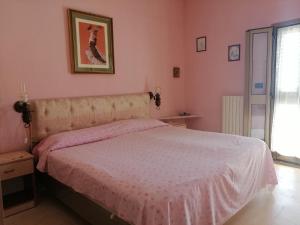 1 dormitorio con 1 cama grande y paredes de color rosa en Casa Christina, en Galatone