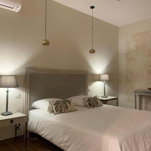 1 dormitorio con 1 cama blanca grande y 2 lámparas en Appartement centre citadelle vue port et falaises, en Bonifacio