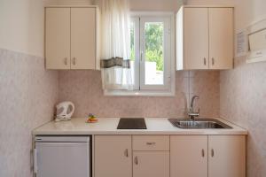 a kitchen with white cabinets and a sink and a window at Irene Studios - Beachfront in Parikia