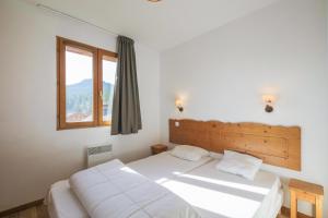een slaapkamer met 2 bedden en een raam bij Résidence le Hameau des Ecrins - maeva Home in Puy-Saint-Vincent