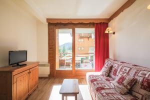 een woonkamer met een bank en een televisie bij Résidence le Hameau des Ecrins - maeva Home in Puy-Saint-Vincent
