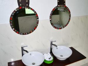 ein Badezimmer mit zwei Waschbecken und zwei Spiegeln in der Unterkunft Osero Lodge in Ololaimutiek