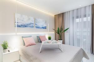 a white bedroom with a white bed and a table at Apartamenty Gardenia Seaside 2 with Sea View by Renters in Dziwnów