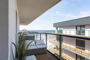 a balcony with a couch and a view of the ocean at Apartamenty Gardenia Seaside 2 with Sea View by Renters in Dziwnów