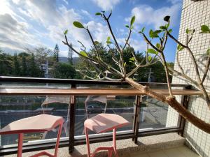 un balcón con 2 sillas rosas y un árbol en On My Way Taitung Hostel en Taitung