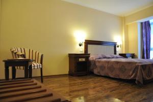 a bedroom with a bed and a table and a chair at Vigo Grand Hotel in Ploieşti