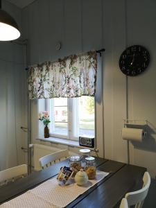 a dining room table with a clock and a window at Villa Korkatti in Haapavesi