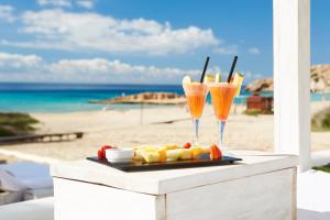 a table with two glasses of drinks on the beach at Insotel Tarida Beach Resort & SPA in Cala Tarida