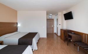a hotel room with two beds and a desk and a television at Rincón Sol in Rincón de la Victoria