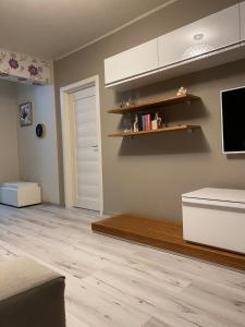 een woonkamer met houten vloeren en een tv aan de muur bij Apartament AVANA in Oradea