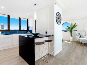 a kitchen with a black counter and stools at Acapulco 2 Bedroom Ocean View Surfers Paradise in Gold Coast