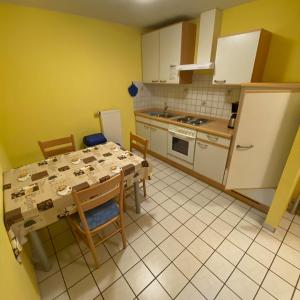 eine Küche mit einem Tisch und Stühlen sowie eine Küche mit gelben Wänden in der Unterkunft Ferienhof Möller 
