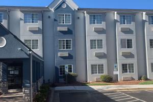 Un edificio de apartamentos con un estacionamiento enfrente. en Microtel Inn by Wyndham Charlotte Airport, en Charlotte