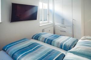 1 dormitorio con 2 almohadas azules y TV en la pared en Ferienwohnung Windspiel, en Warnemünde