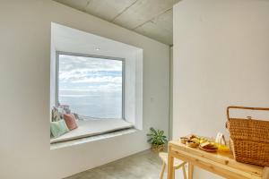 a window in a white room with a table and a bench at Socalco Nature Calheta in Calheta +30 photos