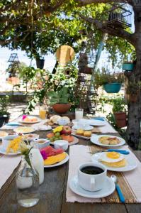 a wooden table topped with plates of food and coffee at Pousada Brisa Do Porto in Porto De Galinhas
