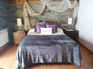 - une chambre avec un grand lit et des oreillers violets dans l'établissement Masia d'en Valentí, à Anserall