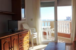 a room with a dresser with a television and a balcony at Apartamentos Turísticos Hawaii 6 in La Manga del Mar Menor