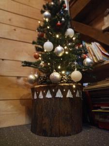 Planinski dom "Tornik" Zlatibor في Ribnica: شجرة عيد الميلاد فوق جذع شجرة