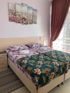 a bed in a bedroom with two paintings on the wall at Вита Гагра in Gagra