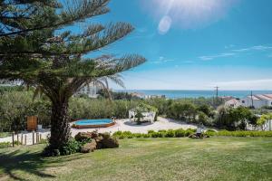 a view of a park with a tree and the ocean at Surf Vilas by Laneez Ericeira in Ericeira