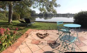 a table and two chairs sitting next to a lake at Les Secrets du Lac in Ardres