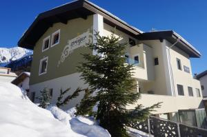 a building with a tree in the snow at Pension Sprenger in San Valentino alla Muta