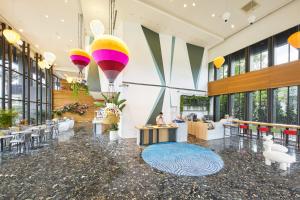 a large lobby with tables and chairs and large windows at Hotel Cham Cham Taitung Caesar Park Hotels & Resort in Taitung City