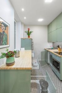 a kitchen with green cabinets and a counter with flowers on it at Art & Comfort Rooms in Kaunas