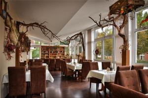 a dining room with tables and chairs and windows at Hotel Zur Linde in Schermbeck