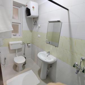 ein Badezimmer mit einem WC, einem Waschbecken und einem Spiegel in der Unterkunft Martam Village Homestay in Gangtok