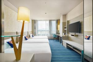a hotel room with four beds and a flat screen tv at Hotel Cham Cham Taitung Caesar Park Hotels & Resort in Taitung City