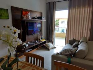 a living room with a couch and a television at Residencial Verano 105C in Guarajuba