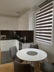 uma cozinha branca com uma mesa e cadeiras brancas em Apartmani Zlatiborio em Zlatibor