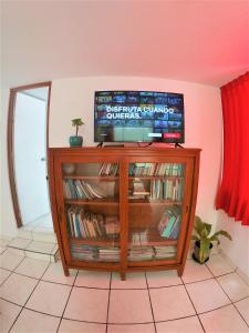 a television sitting on top of a book shelf at Waves Surf Camp Peru in Punta Hermosa