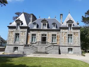 ein altes Steinhaus mit einer großen Treppe davor in der Unterkunft Manoir Le Castel & Villa Beaumaris in Saint-Malo