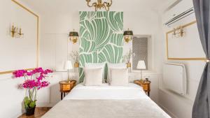 パリにあるLuxury 2 Bedroom - Louvre & Champs Elyseesの白いベッドと緑と白の壁紙が備わるベッドルーム1室が備わります。