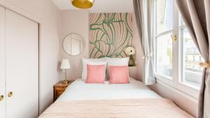 a bedroom with a bed with pink pillows and a window at Luxury 2 Bedroom - Louvre & Champs Elysees in Paris