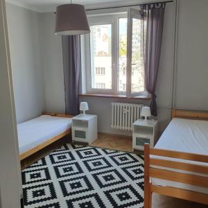 a bedroom with two beds and a window and a rug at GreyT in Toruń