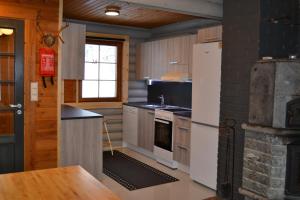 a kitchen with a refrigerator and a stove top oven at Hallanpoika mökki in Hyrynsalmi +12 photos