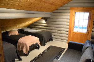 a bedroom with two beds and a window and a couch at Hallanpoika mökki in Hyrynsalmi