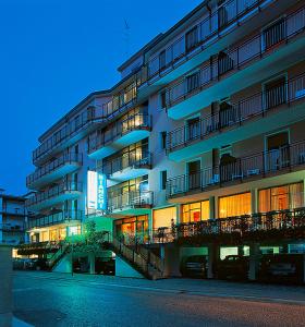un grande edificio con balconi e macchine parcheggiate di fronte ad esso di Hotel Bianchi a Bibione