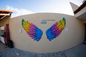 a mural of colorful wings on the side of a wall at Chalés Sol de Milagres in São Miguel dos Milagres