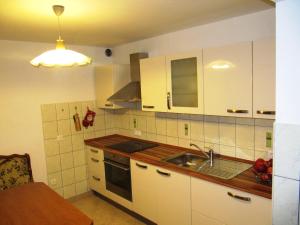 uma cozinha com armários brancos e um lavatório em Holiday Home Češnovar em Raka